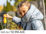 Expressive Portrait of a Young Girl Playing with Bubble Wand, Wearing Padded Jacket in Outdoor Setting. Стоковое фото, фотограф Данила Большаков / Фотобанк Лори