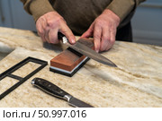 Sharpness concept: Close-up of hands sharpening a knife on a whetstone. Стоковое фото, фотограф Данила Большаков / Фотобанк Лори