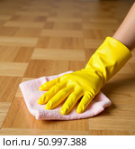 Bright yellow rubber latex gloves are being used to wipe down a polished parquet floor, showcasing a commitment to cleanliness and home upkeep in a warm, inviting space Generative AI. Стоковое AI-изображение, AI-художник Юлия Петровская / Фотобанк Лори