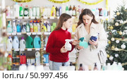 Friendly family, mother and teen daughter, shopping for glass cleaning spray in decorated store during Christmas season, carefully comparing different products. Стоковое видео, видеограф Яков Филимонов / Фотобанк Лори