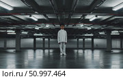 Solitary child wearing white, positioned centrally within empty concrete parking structure, industrial lighting casting stark shadows, expressing profound emotional isolation. Стоковое AI-видео, аниматор Данил Руденко / Фотобанк Лори