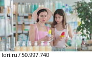 Portrait of interested mother and daughter customers preparing for summer season, holding and examines label and content of mosquito repellent in drugstore. Стоковое видео, видеограф Яков Филимонов / Фотобанк Лори