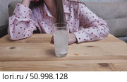 A woman is dissolving an effervescent tablet into a glass of water, which is sitting on a wooden table... Стоковое видео, видеограф Дмитрий Цветков / Фотобанк Лори