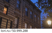 Warm light glowing through brownstone windows in Brooklyn, casting soft illumination across dusk lit street with streetlamp silhouetted against twilight sky. Стоковое AI-видео, аниматор Данил Руденко / Фотобанк Лори