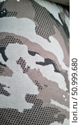 Close-up of a fabric with a camouflage pattern. The print is made in natural tones - a combination of beige, brown, black and gray creates a camouflage effect. The structure of the fabric is clearly visible, which emphasizes the density of the material. The camouflage pattern includes pixelated and smooth transitions, providing versatility for various environmental conditions. This pattern is often used in military uniforms, tactical gear and clothing for active recreation. Стоковое фото, фотограф Анна Кривицкая / Фотобанк Лори