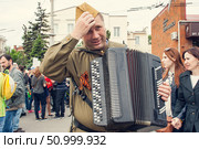 Rostov-on-Don, RUSSIA: - MAY 9, 2016: The action "Immortal regiment" on Victory parade. The celebration of 71 anniversary of Victory in the Great Patriotic War. A man in a military soldier's uniform with a Bayan adjusts his cap. Редакционное фото, фотограф Екатерина Красникова / Фотобанк Лори