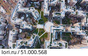 Aerial drone perspective capturing snow blanketed residential buildings, verdant areas, and roadways creating peaceful winter cityscape. Стоковое AI-видео, аниматор Данил Руденко / Фотобанк Лори
