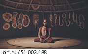 Indigenous shaman sitting cross legged inside thatched hut, surrounded by carved wooden masks, embodying deep spiritual connection with ancestral traditions and ritualistic practices. Стоковое AI-видео, аниматор Данил Руденко / Фотобанк Лори