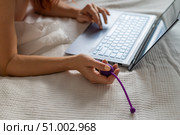 A woman lies in bed holding a vibrator and watching porn on a laptop. Стоковое фото, фотограф Михаил Решетников / Фотобанк Лори