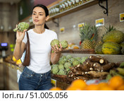 Girl client near vegetable stand in store choose artichoke. Стоковое фото, фотограф Яков Филимонов / Фотобанк Лори