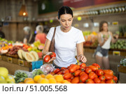 Woman carefully selects fresh tomatoes, standing near the counter in supermarket. Стоковое фото, фотограф Яков Филимонов / Фотобанк Лори