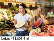 Woman customer in vegetable store examines melon, female seller help. Стоковое фото, фотограф Яков Филимонов / Фотобанк Лори
