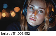 A young woman with striking freckles listens intently to music, surrounded by soft, glowing lights that create a cozy atmosphere. Стоковое AI-видео, аниматор Данила Большаков / Фотобанк Лори