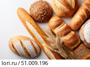 Assortment of Baked bread. Loaf of Bread. Fresh Bakery Products. Healthy Food Concept. Top View. Homemade Sourdough Bread Variety with Flour on a White Background. Wheat Spikes. Close Up. Advertising. Стоковое AI-изображение, AI-художник Марина Демидюк / Фотобанк Лори
