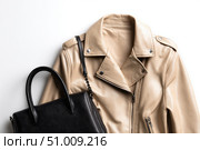Beige leather jacket with zippers and pockets and black leather stylish bag. Modern outerwear. Close-up. Fashion background. Autumn urban street clothes. Fashionable concept. Women's casual day outfit. Стоковое AI-изображение, AI-художник Марина Демидюк / Фотобанк Лори