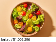 Vibrant salad from fresh lettuce and juicy cherry tomatoes in a ceramic bowl on a beige background. Tomato leafy greens salad with herbs and spices. Healthy food diet cuisine. Fresh nutrition plate. Стоковое AI-изображение, AI-художник Марина Демидюк / Фотобанк Лори