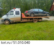 Muddy tow truck with a dark car on its flatbed in a gritty realistic style in silver and brown colors representing vehicle recovery service. Стоковое фото, фотограф Елена Высокова / Фотобанк Лори