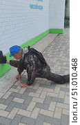 Мужчина в кепке и с рюкзаком в возрасте 78 лет садиться на шпагат на улице. Ведет здоровый образ жизни. Отлично выглядит. Редакционное видео, видеограф Светлана Русских / Фотобанк Лори
