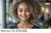 A confident young woman with curly hair smiles warmly in a bright office environment, showcasing positivity and professionalism. Стоковое AI-видео, аниматор Данила Большаков / Фотобанк Лори