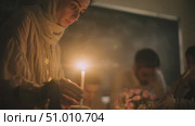 Woman lighting candle during intimate gathering in softly lit room at night. Стоковое AI-видео, аниматор Сергей Толмачёв / Фотобанк Лори