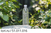 A clear water bottle is showcased surrounded by thriving green foliage, capturing the essence of nature in a serene garden environment. Стоковое AI-видео, аниматор Данила Большаков / Фотобанк Лори