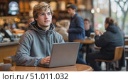 A student focuses on his studies at a cafe, typing on his laptop while others around him enjoy their drinks and conversations. Стоковое AI-видео, аниматор Данила Большаков / Фотобанк Лори