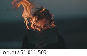 Person reading a book that is on fire during sunset, showcasing a powerful and emotional moment of destruction. Стоковое AI-видео, аниматор Сергей Толмачёв / Фотобанк Лори