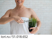 Unrecognizable woman shears a potted plant with scissors. Axillary depilation. Smiling girl removes unwanted vegetation on the body. Armpit epilation concept. Стоковое фото, фотограф Михаил Решетников / Фотобанк Лори