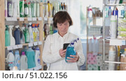 Checking expiration date of spray glass cleaner - male shopper scans QR code on label of spray glass cleaner using her smartphone. Стоковое видео, видеограф Яков Филимонов / Фотобанк Лори