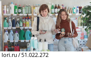 Happy mother with her young daughter choosing different cosmetics in retail store. Стоковое видео, видеограф Яков Филимонов / Фотобанк Лори