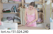 Attentive young tailoress recording dress design on large paper in sewing studio. Стоковое видео, видеограф Яков Филимонов / Фотобанк Лори