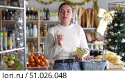 Female shopper with grocery basket attentively choosing fresh food and alcohol in grocery supermarket for Christmas celebration. Стоковое видео, видеограф Яков Филимонов / Фотобанк Лори