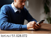 Man using smartphone while sitting at a wooden desk in a modern office during daytime. Стоковое фото, фотограф Сергей Толмачёв / Фотобанк Лори