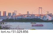 Tokyo, Japan - Oct 13 2024, 4k, panoramic view of Tokyo Bay with a cable-stayed Rainbow Bridge above it, a boat and a water bus sailing, at sunset, Tokyo, Japan. Редакционное видео, видеограф Сергей Богомяко / Фотобанк Лори