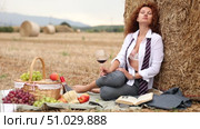 Woman in unbuttoned blouse, shirt does not cover bra, sitting next to haystack in field, reading book, enjoying day off in country. Woman with glass of wine studies material, read literature. Стоковое видео, видеограф Яков Филимонов / Фотобанк Лори