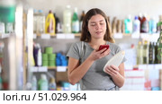 Interested young girl choosing shampoo in personal care store, scanning QR code on bottle using phone to add items to digital cart and process online payment. Стоковое видео, видеограф Яков Филимонов / Фотобанк Лори