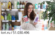 Selective young female customer choosing convenient razor in large retail store. Стоковое видео, видеограф Яков Филимонов / Фотобанк Лори