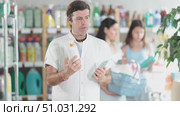 Smiling man with long curly hair comparing sunscreen and tanning lotion, picking best option for summer family vacation in personal care store while wife and daughter browsing products in background. Стоковое видео, видеограф Яков Филимонов / Фотобанк Лори
