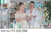 Pregnant girl looking for pills in a pharmacy. Female pharmacist helps to choose the right pills. Стоковое видео, видеограф Яков Филимонов / Фотобанк Лори