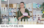 Middle-aged woman holds a pack of pads for her period. Customer chooses hygiene products in a pharmacy. Стоковое видео, видеограф Яков Филимонов / Фотобанк Лори