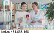 Asian female client choosing cream or skin care product in modern pharmacy and scan QR code on label, young woman pharmacist consulting and offering variety of goods to customer. Стоковое видео, видеограф Яков Филимонов / Фотобанк Лори