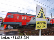 Безопасность на железной дороге. Знак "Берегись поезда!" и проносящаяся электричка. Редакционное фото, фотограф Александр Тарасенков / Фотобанк Лори