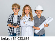 Three children dressed as professionals, one with a calculator, another in a hard hat and goggles, and the last holding blueprints, showcasing future career aspirations and teamwork. Стоковое AI-изображение, AI-художник Ирина Ручушкина / Фотобанк Лори
