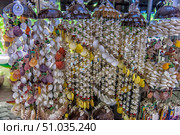 Bright and colorful seashell pendants, collected in decorative garlands. An exotic souvenir, popular at tropical resorts. Decorations made of natural materials create an atmosphere of the sea and summer vacation. Стоковое фото, фотограф Анна Кривицкая / Фотобанк Лори