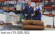 Elderly man and young guy warehouse workers in uniform discuss documents. Стоковое видео, видеограф Яков Филимонов / Фотобанк Лори