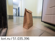 An eco paper bag is standing in the lobby on the doorstep of the apartment. Contactless food delivery to the epidemic. The courier left an online order at the entrance. precautionary measures. Стоковое фото, фотограф Михаил Решетников / Фотобанк Лори