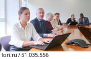 Young caucasian woman sitting at desk in meeting room and using laptop duting conference. Стоковое видео, видеограф Яков Филимонов / Фотобанк Лори