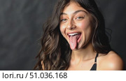 A young woman expresses her playful nature, sticking her tongue out and smiling brightly while posing in a studio, highlighting her vibrant character. Стоковое AI-видео, аниматор Данила Большаков / Фотобанк Лори