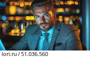 A man in formal attire concentrates on his laptop late at night, illuminated by city lights streaming through the window. Стоковое AI-видео, аниматор Данила Большаков / Фотобанк Лори