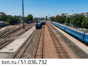 Multiple blue carriages stationed on separate tracks, station buildings, signal masts, semaphore signal, catenary poles, turnout switches, sidings and urban landscape, operational railway environment. Стоковое фото, фотограф Андрей Ка / Фотобанк Лори